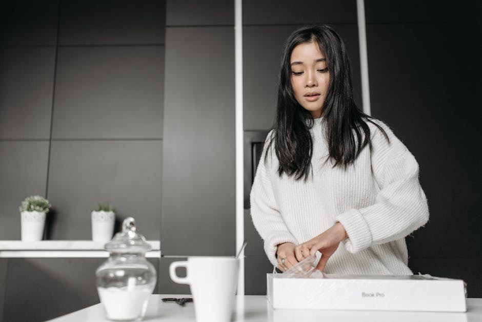 Young woman opening a box in a contemporary kitchen, surrounded by modern decor.