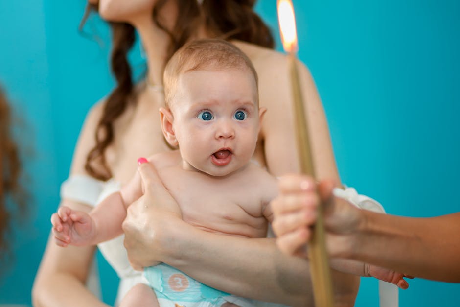 A child held during a baptism ceremony with a lit candle symbolizing faith.