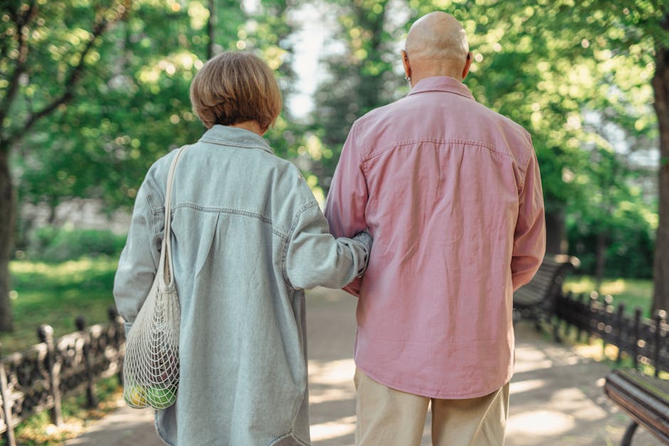 A senior couple walking together in a sunlit park, enjoying their time outdoors.