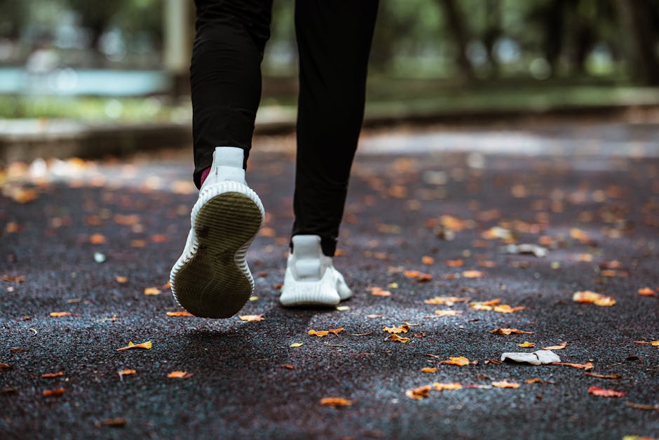 Legs of anonymous person in white sneakers and black leggings running on sidewalk