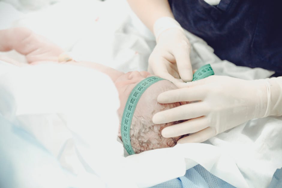 A healthcare professional measures a newborn baby's head circumference in a hospital setting.