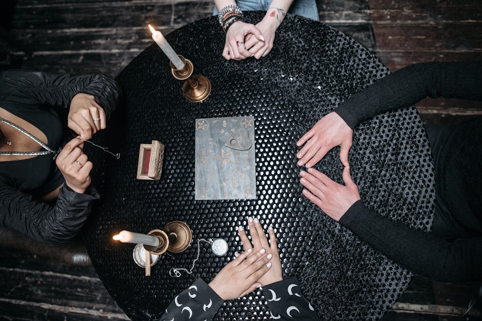 Top view of people conducting a seance around a mystical table with candles and a pendulum.
