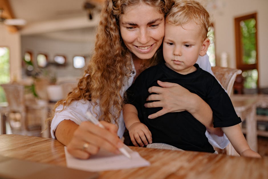 Mother holding her young child while writing, creating a bonding moment indoors.