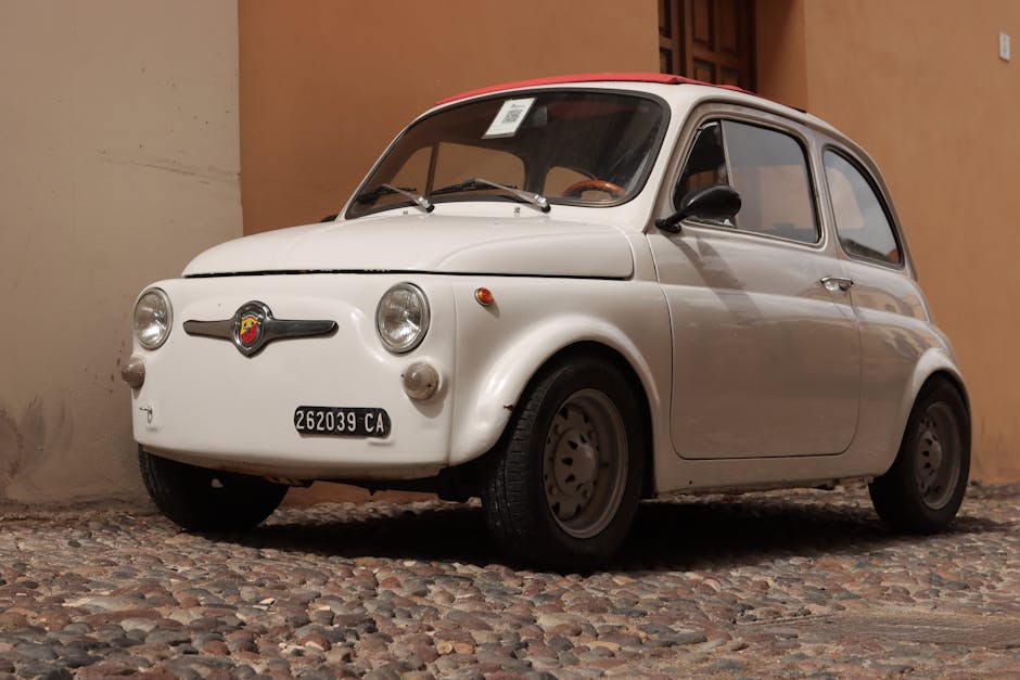 Vintage Fiat 500 parked on a rustic cobblestone street, capturing classic automotive charm.