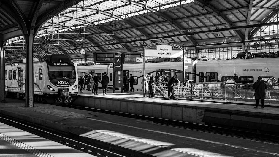 A vibrant train station scene captured in black and white, bustling with people.