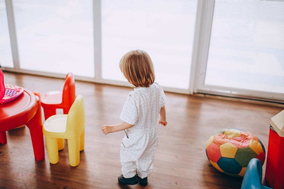 Young child in a colorful playroom with toys and child-sized furniture.