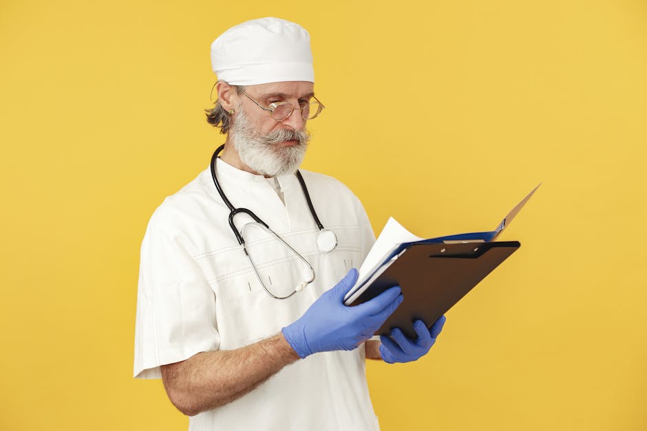A bearded male doctor with stethoscope reviews medical documents on a yellow background.