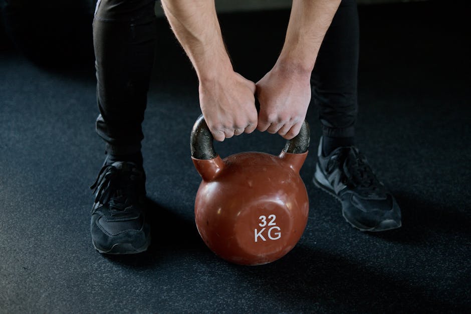 A person lifting a 32 kg kettlebell in a gym setting, showcasing strength training.