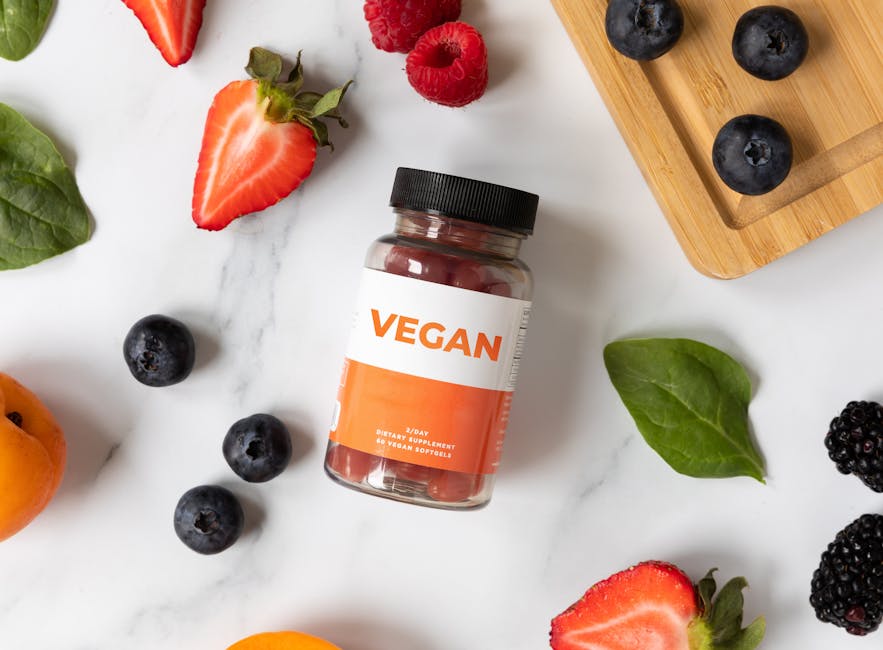 A flat lay of vegan supplements surrounded by fresh fruits on a white marble surface.