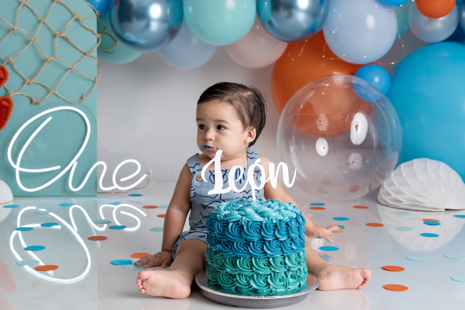 Cute baby celebrating first birthday with cake and balloons.
