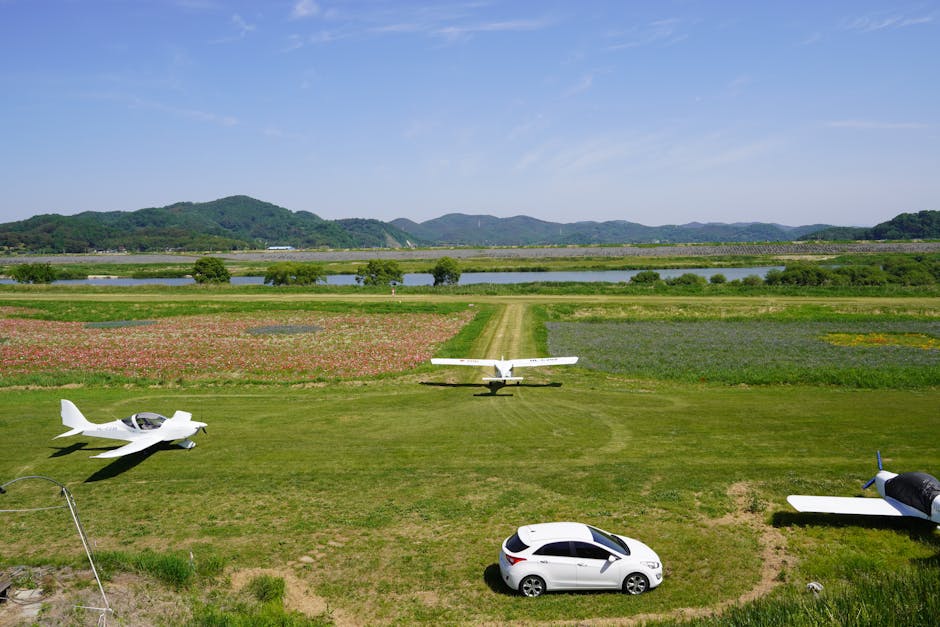 A peaceful rural scene with small planes, fields, and a car in view on a sunny day.