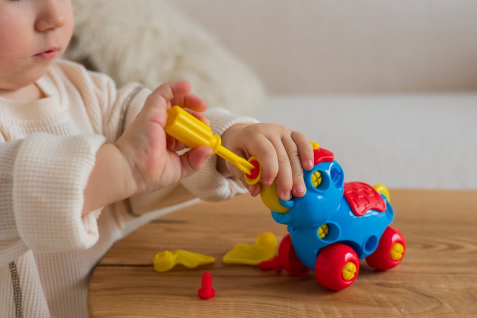 Close-up of a baby engaged with a vibrant toy car on a wooden table.