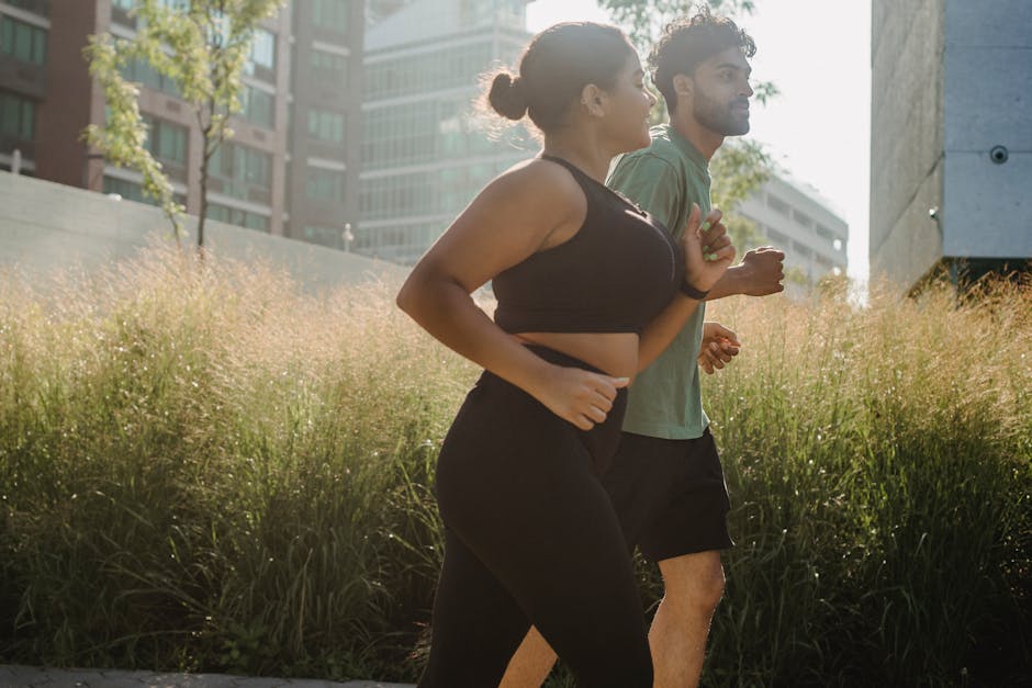 Two adults jogging in an urban park surrounded by greenery, enjoying a healthy lifestyle.