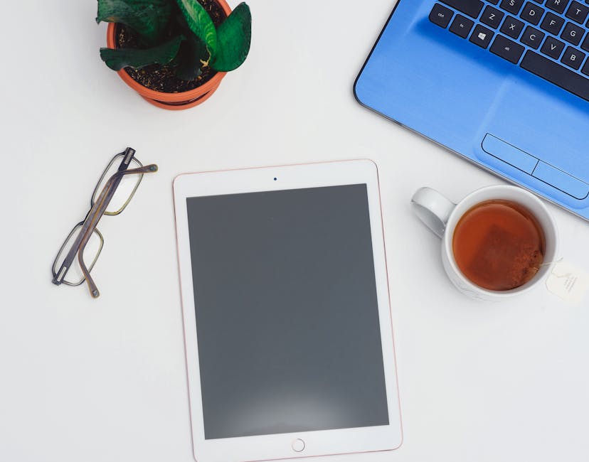 A modern workspace setup featuring a tablet, laptop, and a cup of tea for productive work sessions.