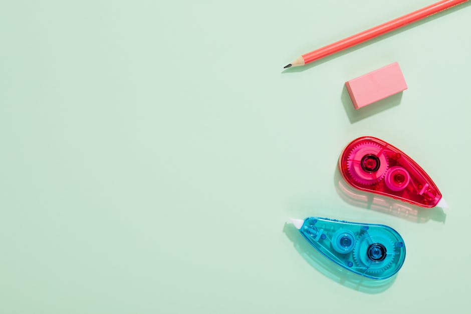 Arrangement of pencil, eraser, and correction tape on a pastel surface.