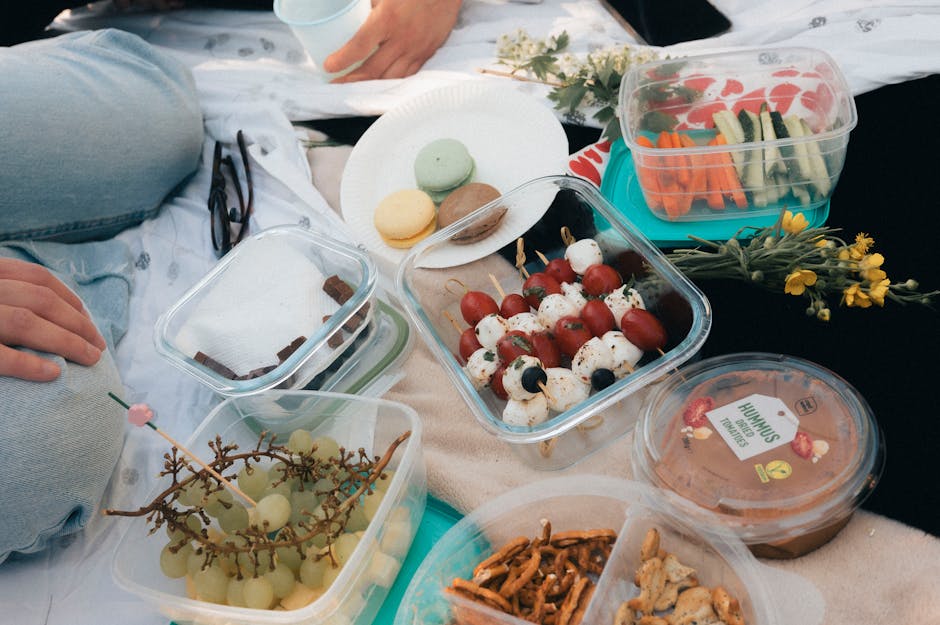 A delightful picnic setup with fresh fruits, vegetables, hummus, and macarons on a sunny day.