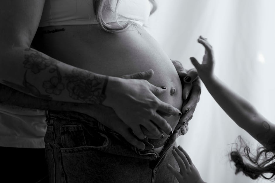 Tender black and white photo showing family hands on pregnant belly, highlighting love and connection.