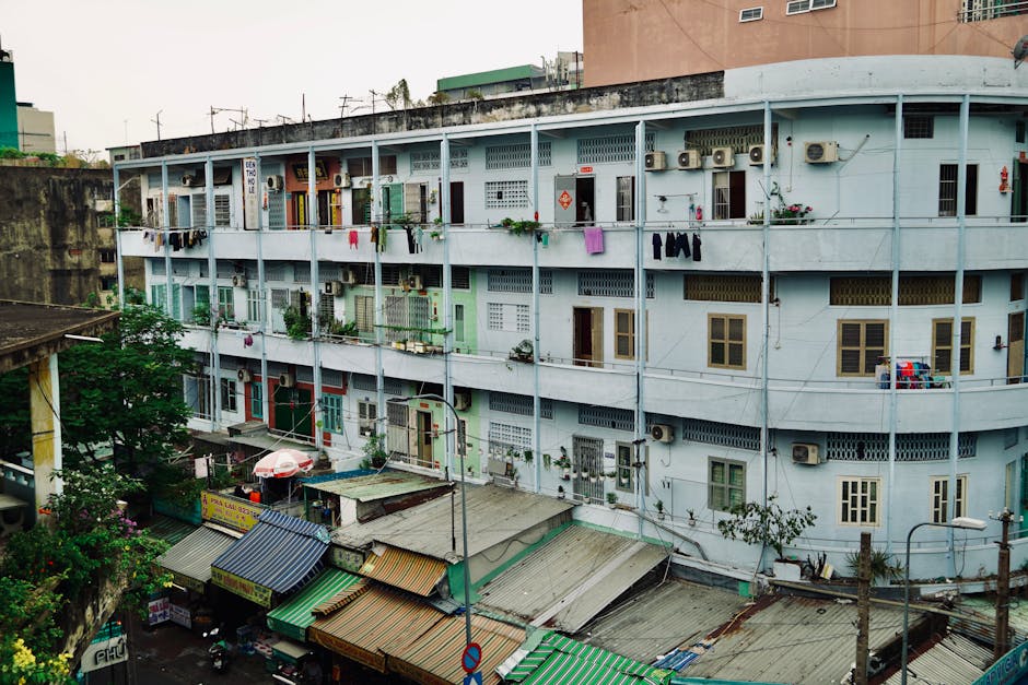 A street-level view of a multi-story apartment building with visible laundry and air conditioners.