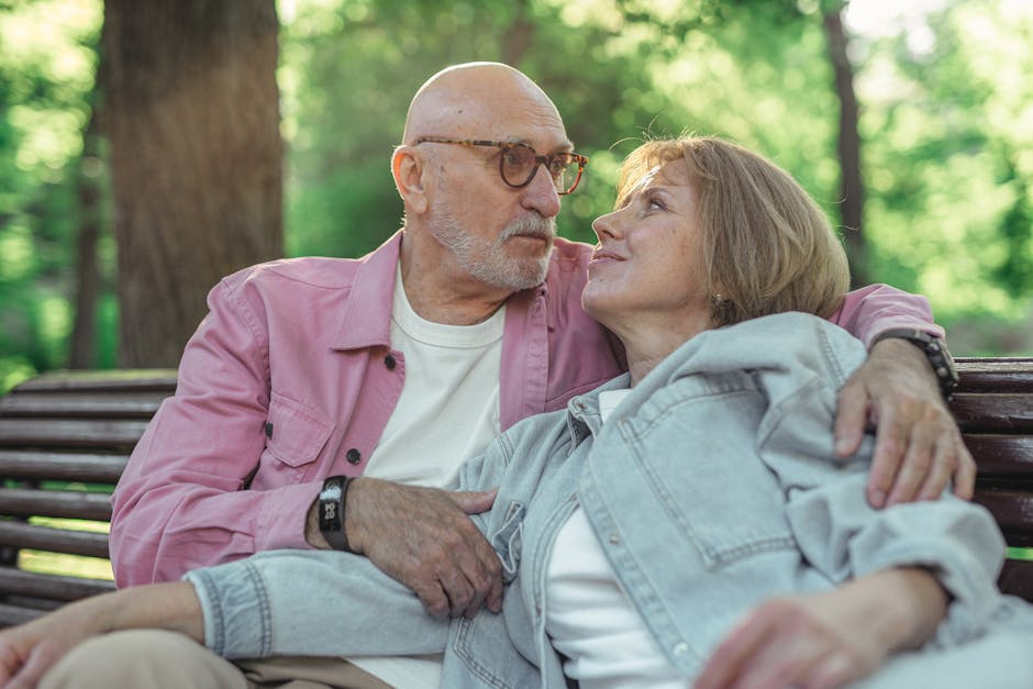 Senior couple sitting on a wooden bench outdoors, expressing love and togetherness.