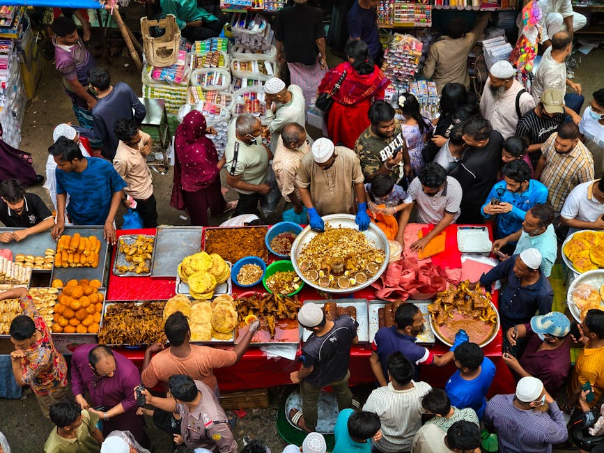 Overhead view of a bustling street food market with diverse people and colorful snacks.