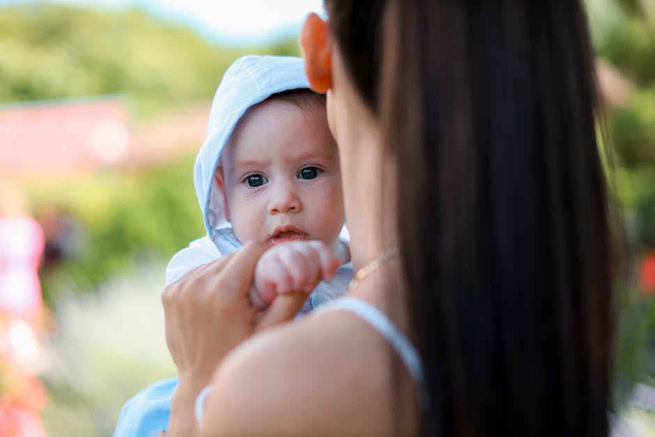 A mother tenderly holds her baby while enjoying a sunny day outdoors.