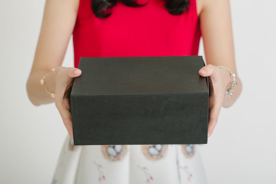 Woman holding a black gift box in a red top, showcasing elegance and surprise.