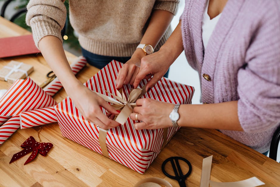 Two people wrapping a striped gift box with ribbon, evoking a festive holiday mood.
