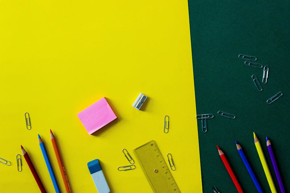 Top view of colorful school supplies on a vibrant yellow and green background.
