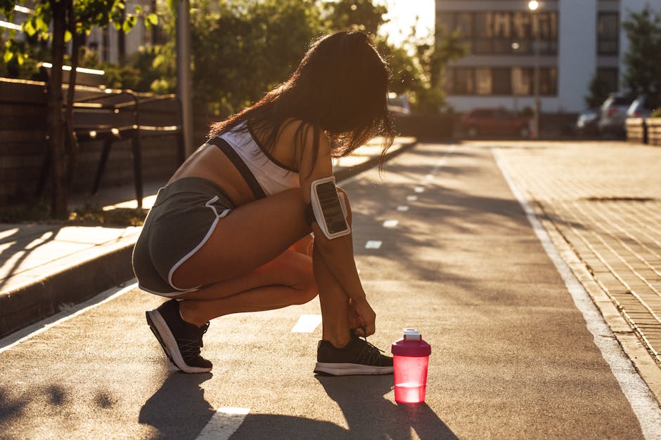 Woman tying shoes on a sunny morning with a sports drink, readying for an outdoor workout.