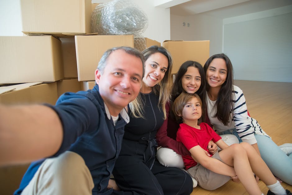 A family smiling and taking a selfie among moving boxes in their new home.