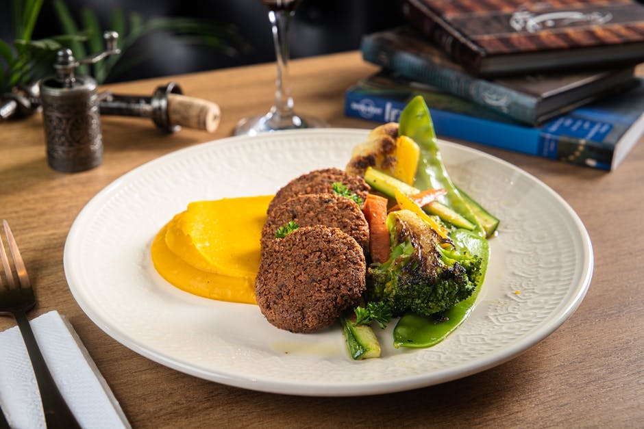 Delicious vegan meal with falafel, mashed squash, and grilled vegetables on a plate.