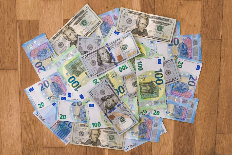 Aerial view of mixed Euro and US Dollar banknotes on a wooden floor, symbolizing global finance.