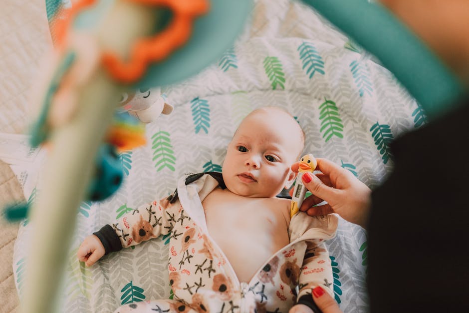 Cute baby lying indoors with a thermometer, wearing a patterned onesie.