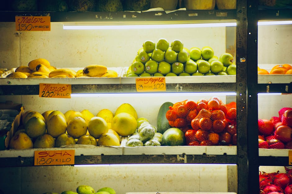 A colorful display of fresh fruits on grocery store shelves, including apples, mangoes, and more.