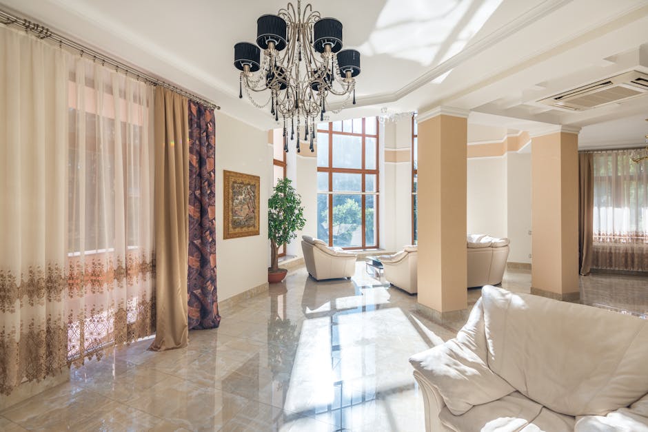 Spacious living room featuring elegant chandelier, large windows, and plush seating.