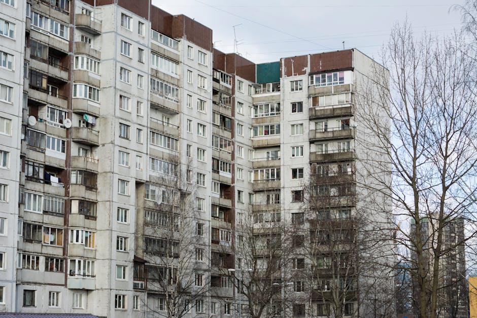 Concrete apartment complex with multiple windows and trees in an urban setting.