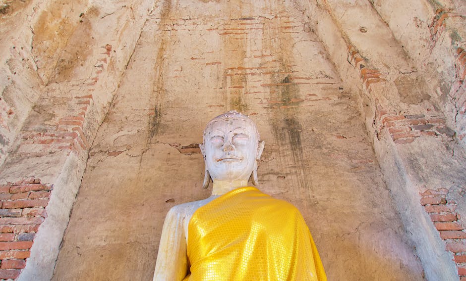 Front view of a serene Buddha statue draped in yellow, in Ayutthaya, Thailand.