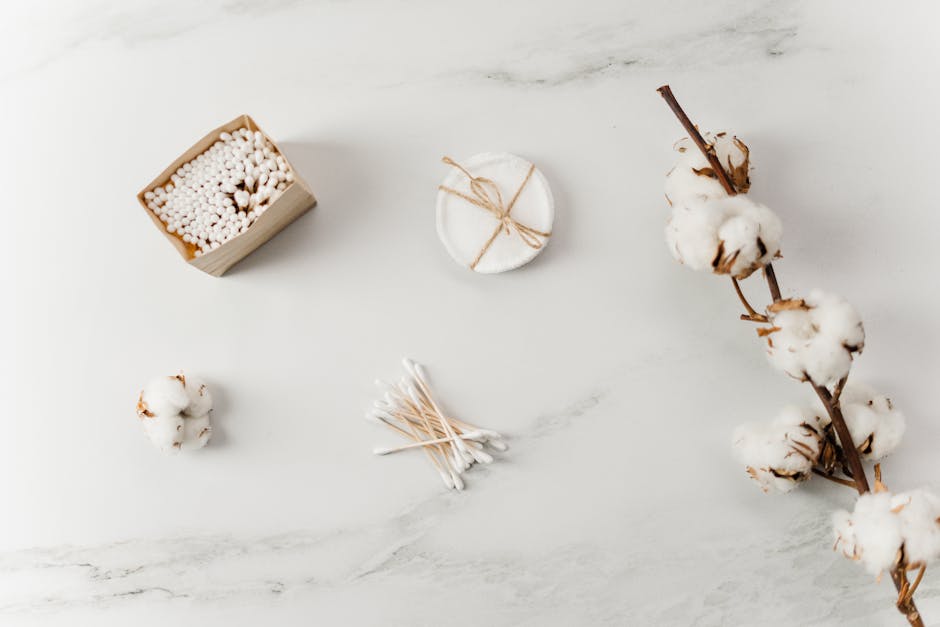 Elegant flat lay featuring cotton branches, toiletries, and cotton swabs on a marble surface.
