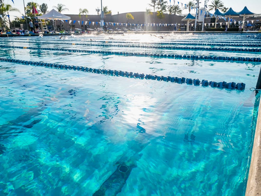 Crystal clear blue water in an outdoor swimming pool with lanes on a sunny day.