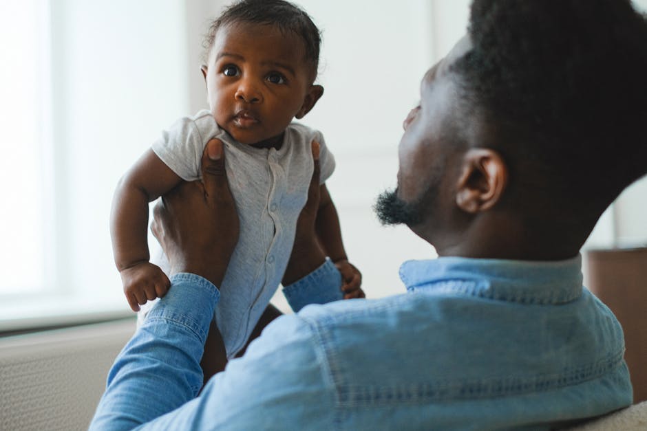 A father joyfully holds his baby in a bright, loving indoor environment.