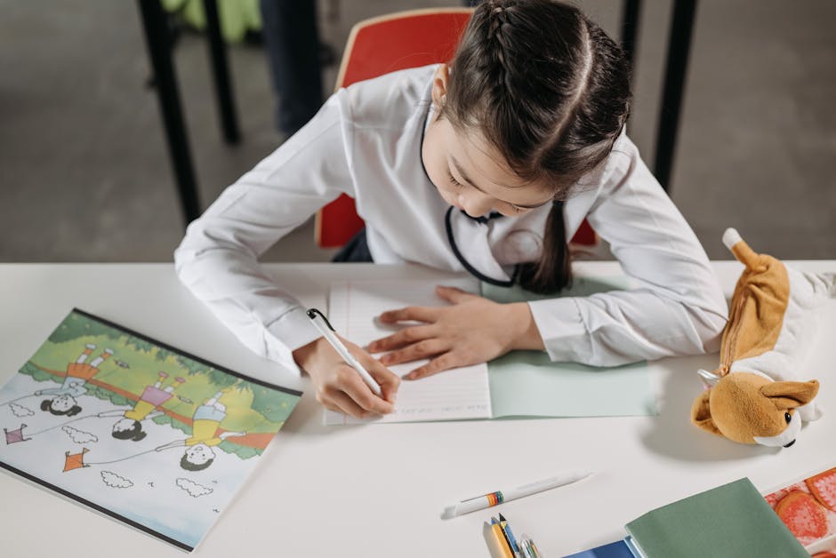 A young girl focused on homework, writing in a notebook in a classroom setting.