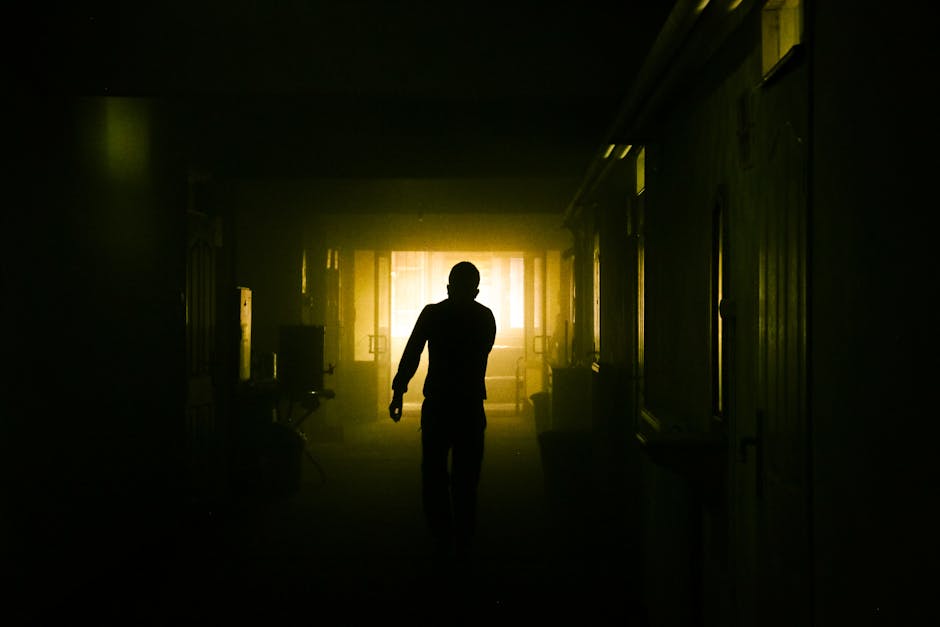 A mysterious silhouette of a person in a dimly lit corridor with dramatic lighting.