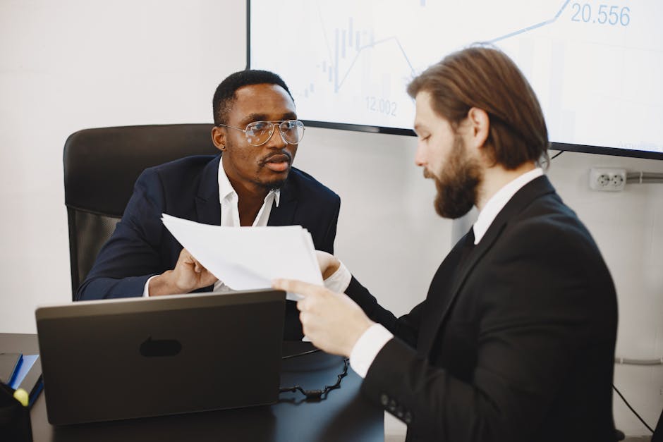 Professionals examining documents in an office business meeting setup.