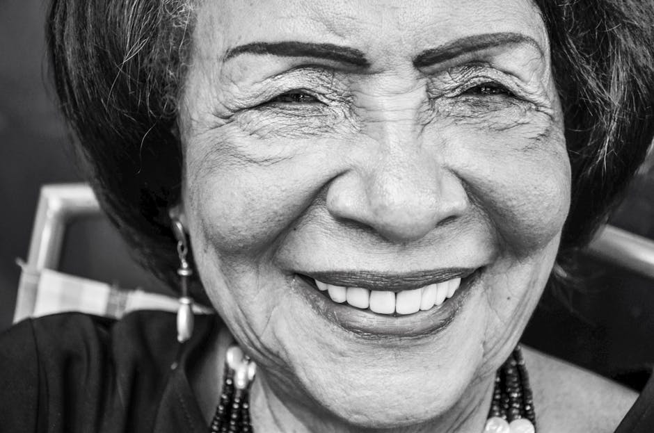 Close-up black and white portrait capturing the genuine smile of a senior woman.