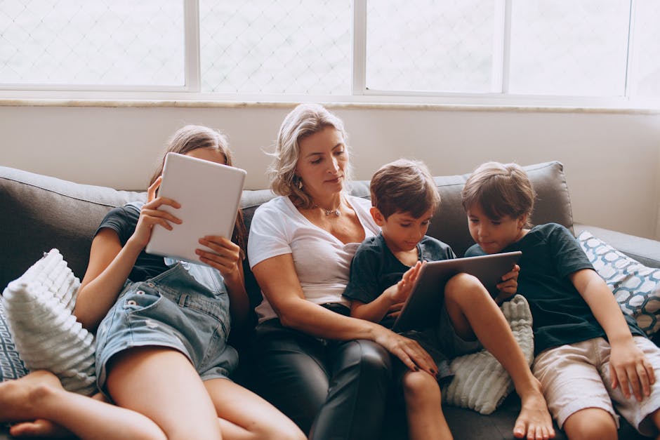 A family of four using tablets while relaxing on a sofa in a living room, creating a cozy indoor scene.
