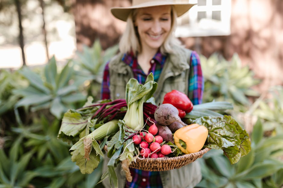 Smiling woman holding fresh farm produce in a basket outdoors, showcasing colorful vegetables.