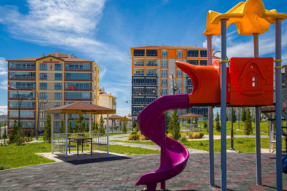 Vibrant playground with a slide in a green urban park amidst modern buildings.