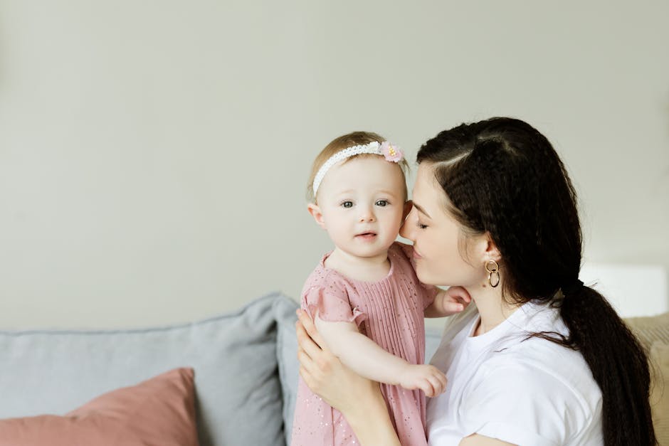 Tender moment of a mother kissing her baby daughter. Warm and loving family scene indoors.