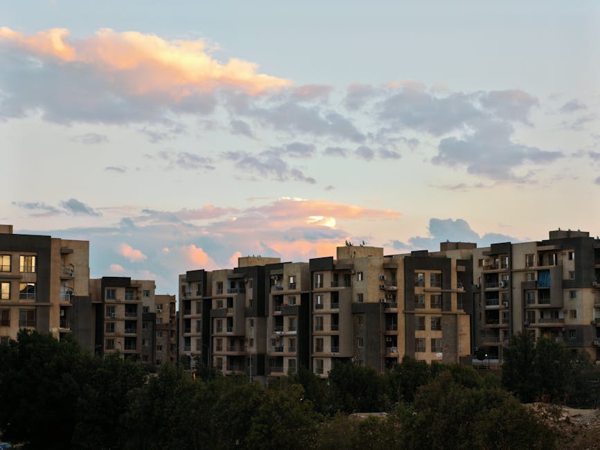 A block of residential apartments under a colorful sunset sky with scattered clouds.