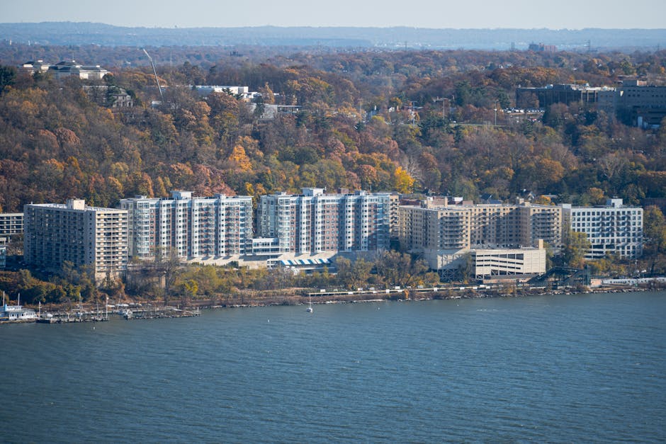 Aerial shot of riverside apartments surrounded by autumn foliage.